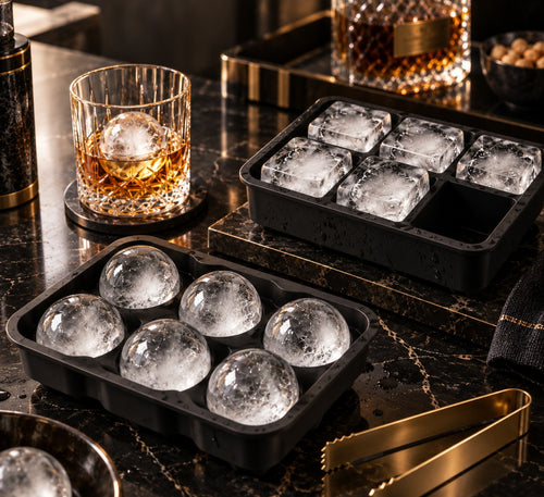 Duo de moules à glaçons en silicone noir, 6 sphères et 6 cubes de glace, à côté d'un verre de whisky