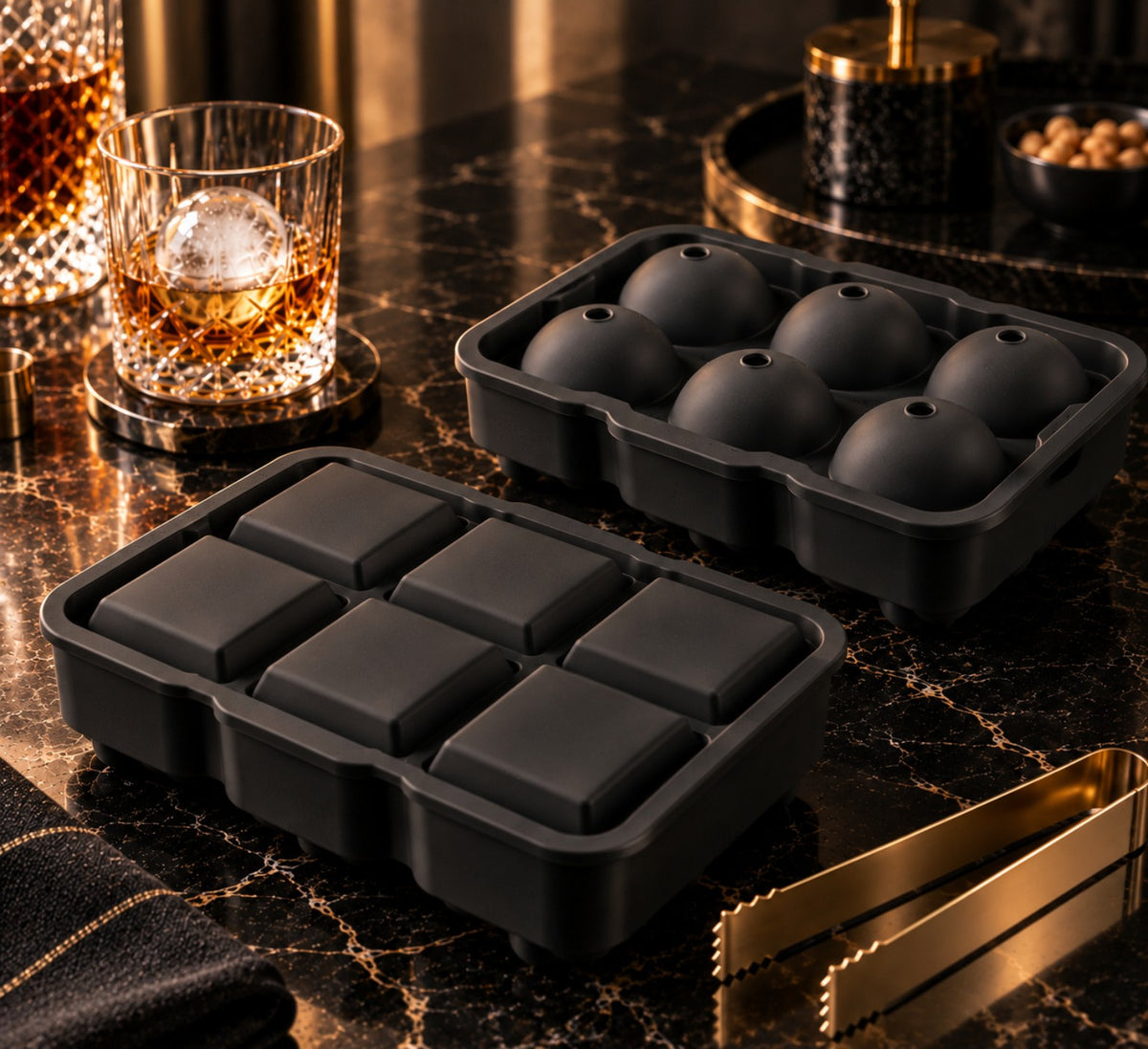 Les deux moules à glaçons en silicone noir, 6 sphères et 6 cubes, sur un plan en marbre
