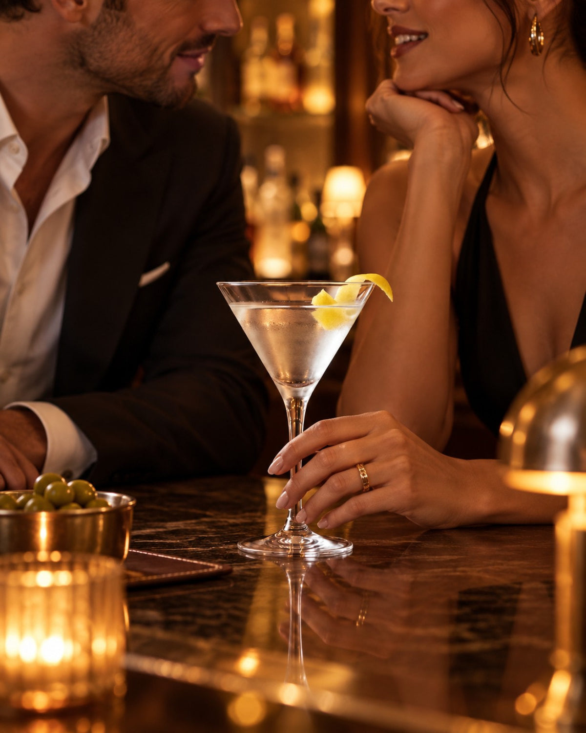 Verre à martini garni d'un zeste de citron, tenu en main au comptoir d'un bar