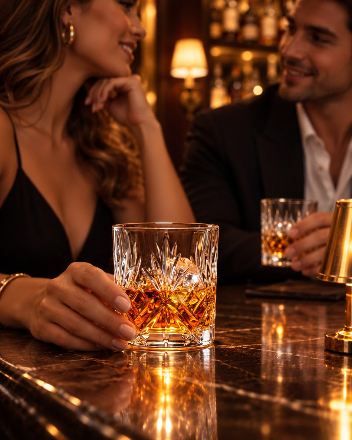 Tumbler à whisky en cristal taillé tenu en main au comptoir d'un bar